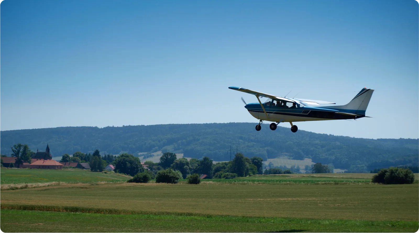 Small aircraft flies over grass strip - featured image.