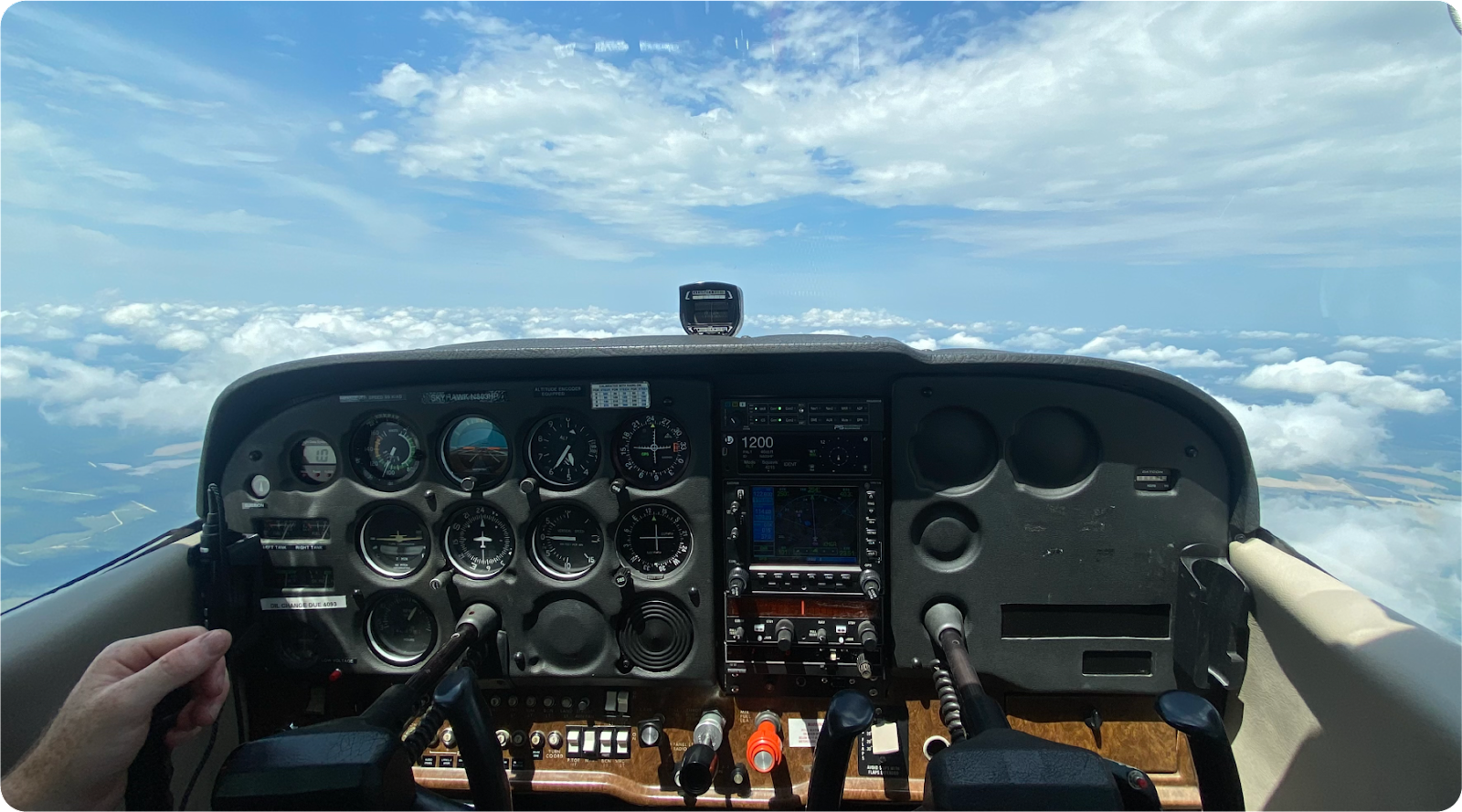 Cockpit of a Cessna flying over scattered clouds.