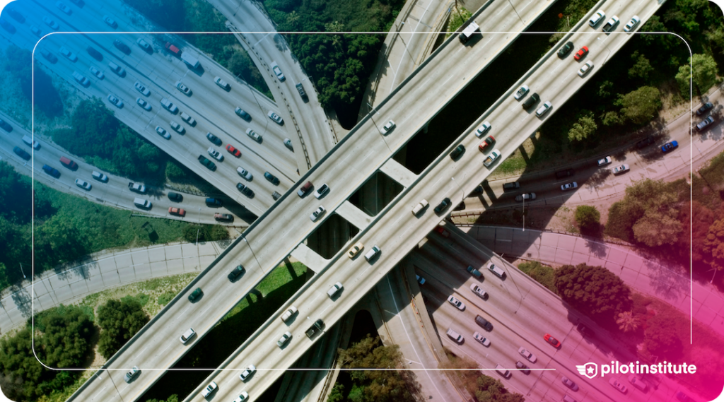 Aerial view of a busy highway interchange with multiple lanes and cars. Pilot Institute logo included.